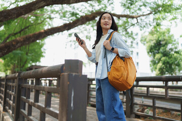Young woman navigating city park with smartphone © Phimwilai