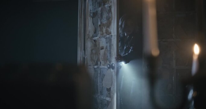 Woman entering scary room and propping door open as lightning flashes outside - steady cam shot