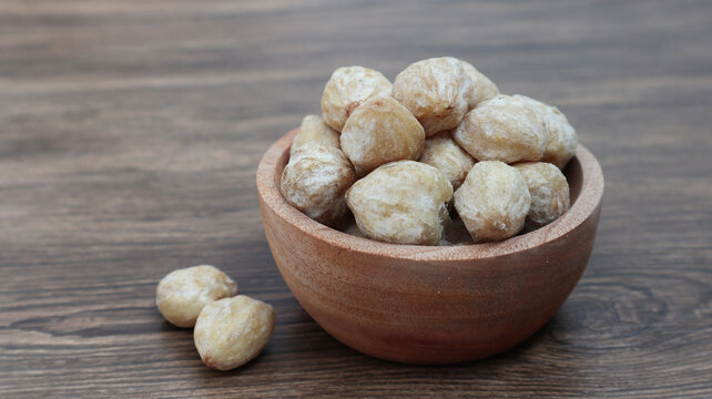 Close up of candlenut or kemiri on the bowl. Isolated on wooden background
