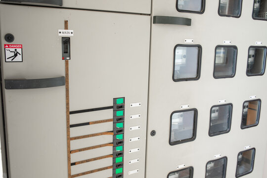 Row of industrial electrical switchgear panels with multiple green status indicators circuit breakers and control elements in building in Asia