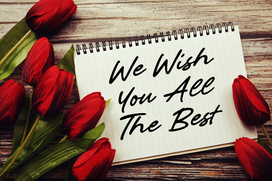 We Wish You All The Best text written on notepad with flower decoration on wooden background