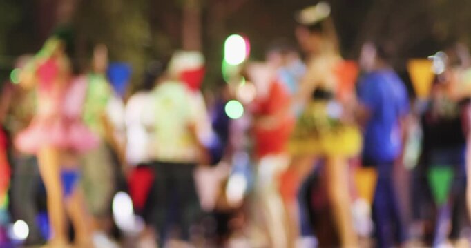 Blurred people dancing on concert stage with colorful lights at night. Retro folk dance in Traditional Thai temple fair, Energetic live music, party, festival, and entertainment atmosphere background