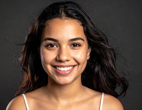Smiling Young Woman with Long Dark Hair Facing Camera in Studio Portrait