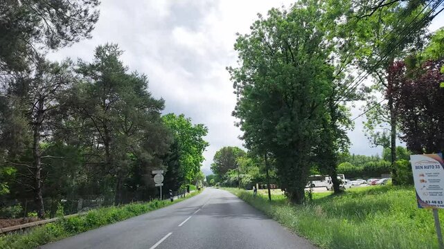 Driving Down a Suburban Road Lined with Green Trees in Paris France