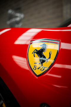 Close up focuses on Ferrari prancing horse crest with SF initials on a glossy 488 Spider body panel indoors, soft lights reflect, shallow depth isolates the emblem.