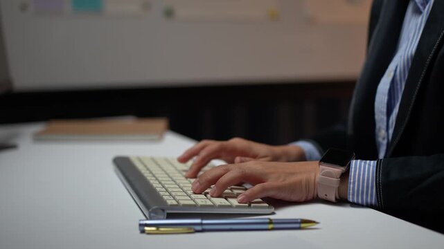 Businesswoman hands typing on a modern computer keyboard at night