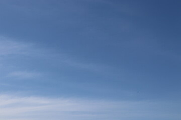 Obraz premium Clear blue sky background with light soft white clouds texture on a bright sunny day
