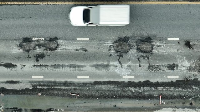 Aerial drone view of severely damaged asphalt highlights infrastructure decay, neglected maintenance, safety hazards, public investment gaps, environmental risk, and urgent repair needs.
