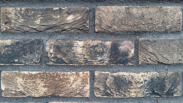 Grunge beige brick wall macro texture, rustic burnt clinker brickwork background with black soot details