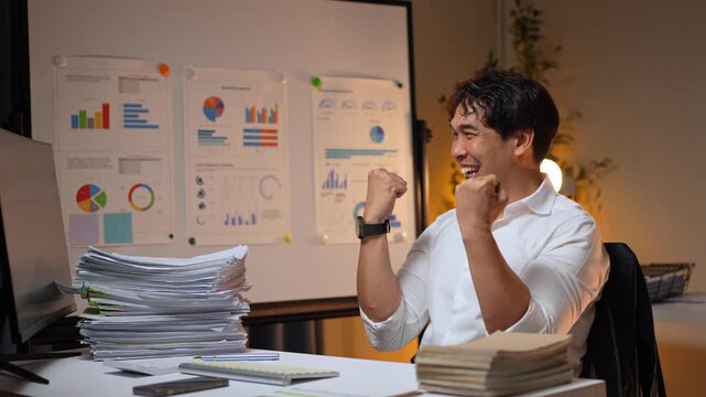 Successful businessman celebrating achievement working late in office
