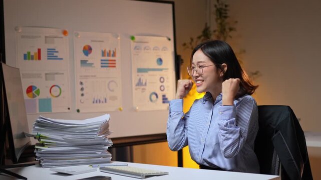 Successful businesswoman celebrating achievement working late at night