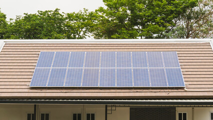 Fototapeta premium Solar panels installed on the roof of a house with green trees in the background. Concept of renewable energy, eco-friendly living, and alternative sustainable power for modern homes.