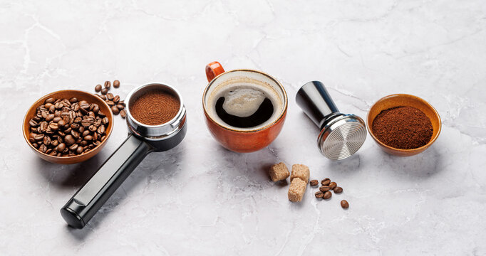 Coffee beans and espresso tools on white marble background
