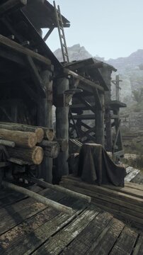 A wooden structure stands with logs stacked nearby. Scaffolding is visible as the area shows signs of construction. The setting is surrounded by rocky hills under a clear sky.