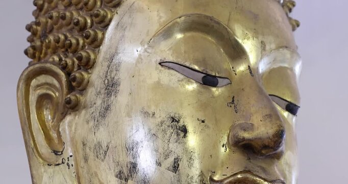 Golden Buddha statue details showing robe texture and peaceful facial expression, symbolizing spirituality, faith, Buddhism culture and Thai heritage, close-up