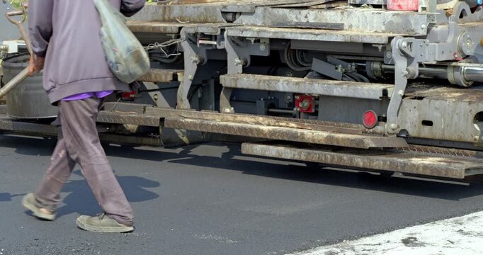 Workers lay asphalt in an urban setting illustrating paving process for road construction.