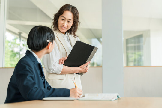A female student in a school uniform studying at a cram school or preparatory school, and a female instructor teaching her.