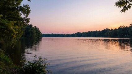 Obraz premium Calm lake reflecting pastel sky at sunset with treeline