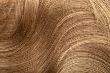 Fototapeta premium Blond hair close-up as a background. Women's long blonde hair. Beautifully styled wavy shiny curls. Hair coloring. Hairdressing procedures, extension.