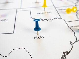 Close-up  image showing a US map focusing on Texas with a blue pushpin. Yellow pins mark neighboring states, perfect for themes of travel planning, business logistics, and regional targeting. © RODWORKS