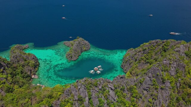 High altitude aerial orbit shot showcasing the spectacular scale of Twin Lagoon and limestone karsts in Coron.