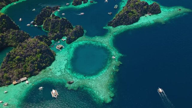 Aerial rocket shot ascending vertically over a circular turquoise lagoon and limestone cliffs in Coron, Palawan.