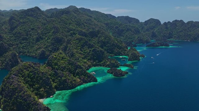 Drone forward diagonal tracking shot over spectacular limestone karsts and turquoise lagoons in Coron, Philippines.