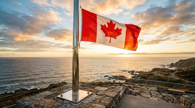 National flag of Canada waving on a polished metal flagpole at a stone coastal lookout overlooking the ocean during a golden hour sunset with a cloudy sky and rocky cliffs.