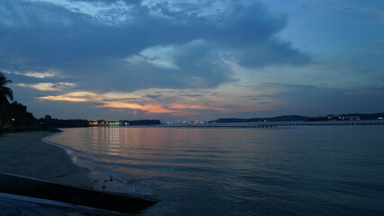 Obraz premium Tranquil Twilight at Coastal Beach with Distant City Glow