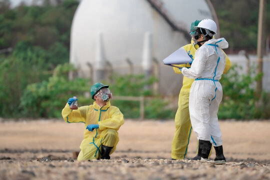 Environmental scientists collecting polluted water samples and reviewing inspection documents near industrial chemical tanks during hazardous contamination assessment project.