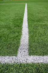 Close up view of white field marking line on green artificial grass football pitch. Sports background with texture and perspective. © o_lypa