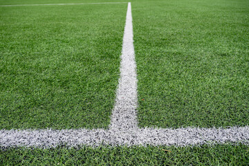 Close up view of white field marking line on green artificial grass football pitch. Sports background with texture and perspective. © o_lypa