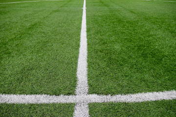 Obraz premium Close view of center circle and kickoff mark on green artificial turf football field. Sports background with white field lines and stadium surface details.