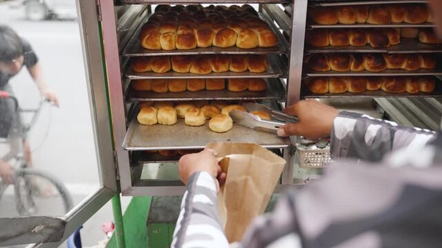 Street Vendor Placing Moringa Pandesal in Paper Bag While Customer Pays at Street Stall
