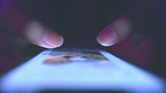 Finger of woman touching scroll page app on mobile phone.In a room with blue and purple neon tones.concept Social media and marketing