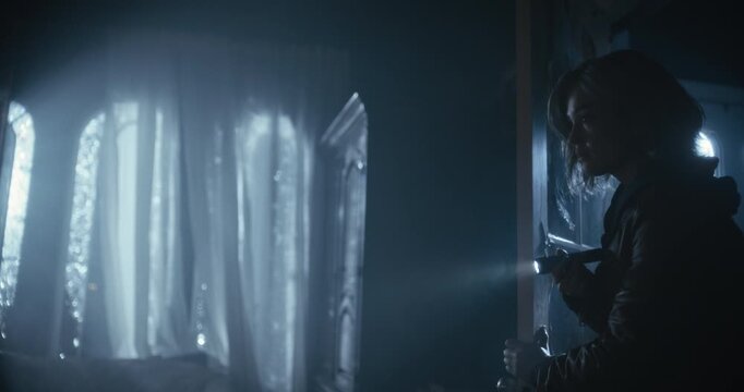 Profile, silhouette of woman with flashlight entering dark and scary room then opening chest on glowing desk as storm rages outside