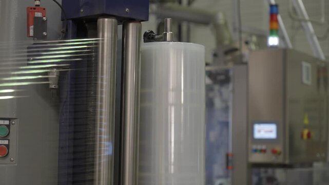 Industrial stretch wrapping machine rolls transparent film around a pallet