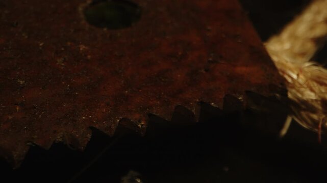 Horror concept: Detailed macro dolly of a rusty and filthy saw and bloody ropes