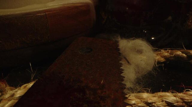 Unsettling dolly out of a rusty saw covered in blood surrounded by broken glass and bloody ropes