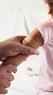 Doctor, hands and kid with plaster on bed for immunization or medical injection in home visit. Healthcare, pediatrician and child with first aid bandage for nursing, vaccination or wound protection