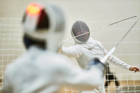 Competitive fencers in action during intense indoor fencing match