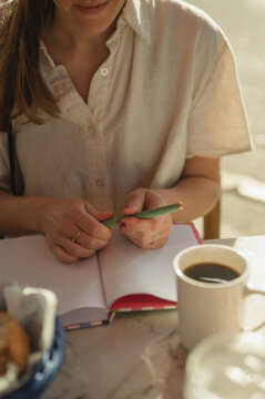 Young woman journaling at a cafe table with coffee in the morning