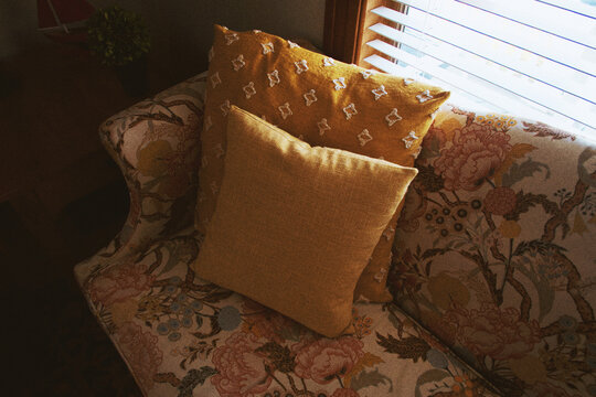 Cozy floral couch with pillows by sunny window