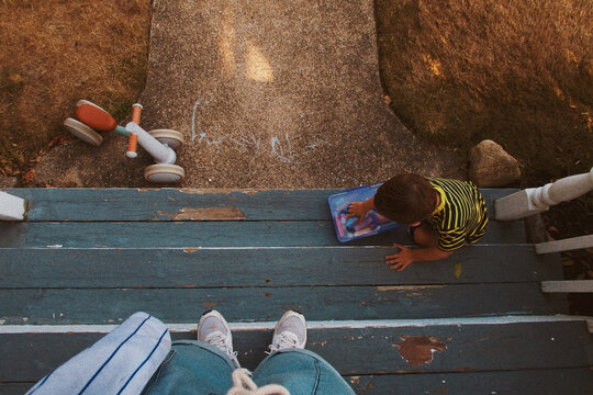 Parent watching child play with chalk on the front stoop