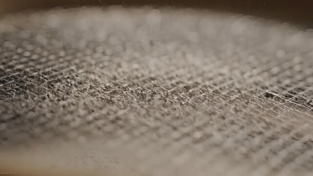 Closeup of fine particles falling through a sieve.