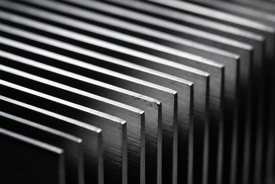 Graphic close-up of parallel cooling fins on a milled aluminium heatsink. Mesmerizing silver lines and deep black shadows reveal microscopic extrusion textures and industrial exposure dings.