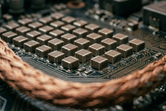 Hardware close-up of rows of matte-brown ceramic SMD capacitors on a motherboard. Midground components are tack-sharp alongside granular solder joints, framed by a soft blurred copper wire.