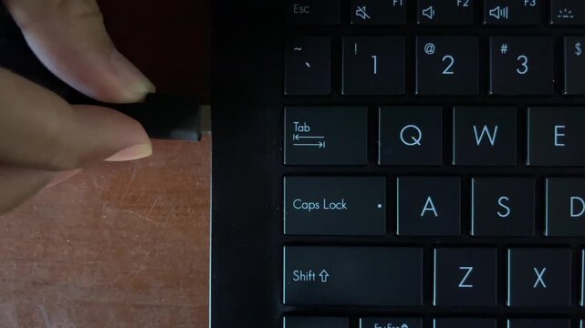 Close Up of Hand Plugging Power Charger Cable Into Laptop Port