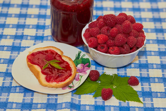 Slice of bread with raspberry jam and fresh raspberries, A slice of white bread spread with vibrant red raspberry jam, topped with a fresh berry