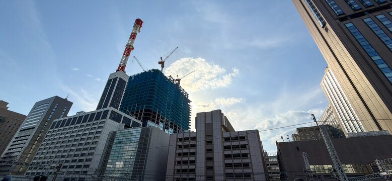 青空の下で建設が進む都市の高層ビルとクレーンの景観